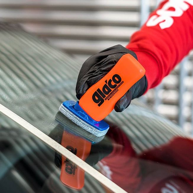 Hand mit Glaco DX Glasversiegelung auf Autoscheibe in der Nähe von weißem Klebeband