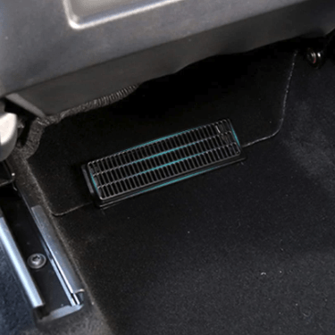 Sort gitter-cover til ventilationskanalen monteret under bagsædet i en Tesla Model Y