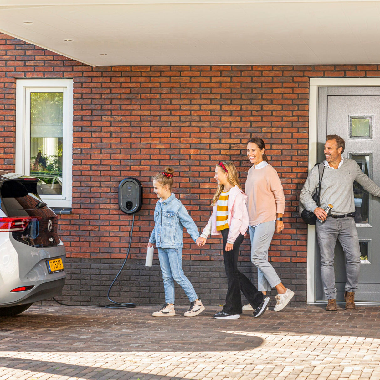 Familie verlässt Haus mit an Ratio smart Ladestation angeschlossenem Elektroauto