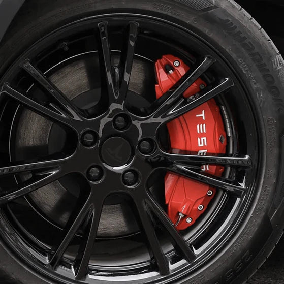 Rote Bremssattel-Abdeckungen mit weißem Tesla-Logo auf einer schwarzen Felge.