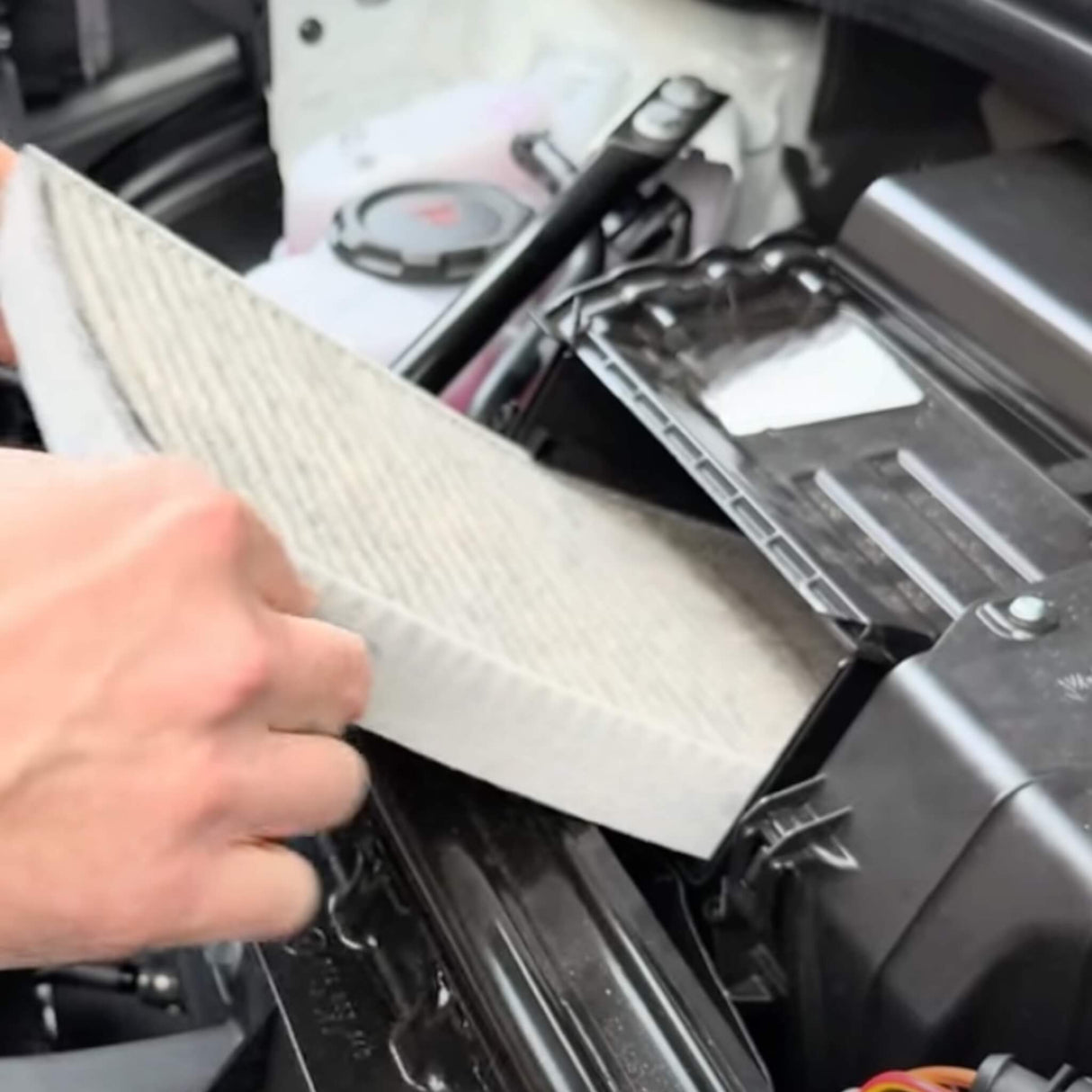 Eine Hand setzt einen Kohle-Luftfilter im Motorraum eines VW ID.3/4/5/6/7 ein.