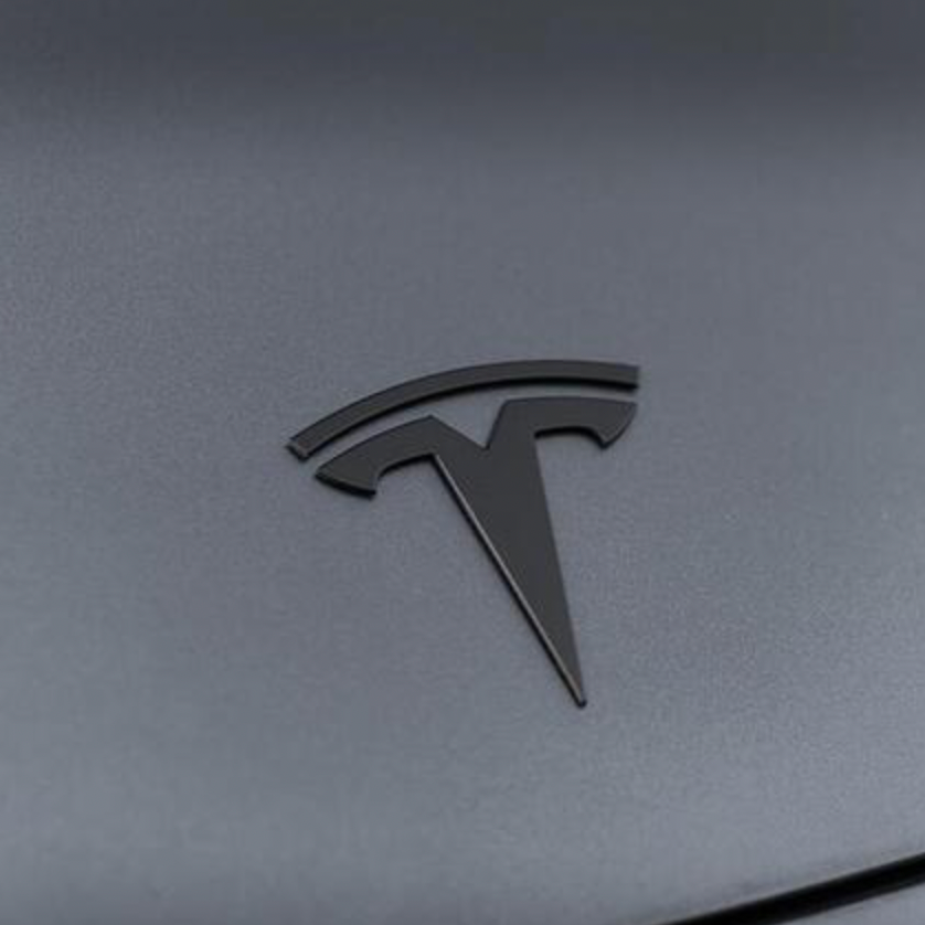 Mat sort Tesla-emblem i metal monteret på Tesla Model 3