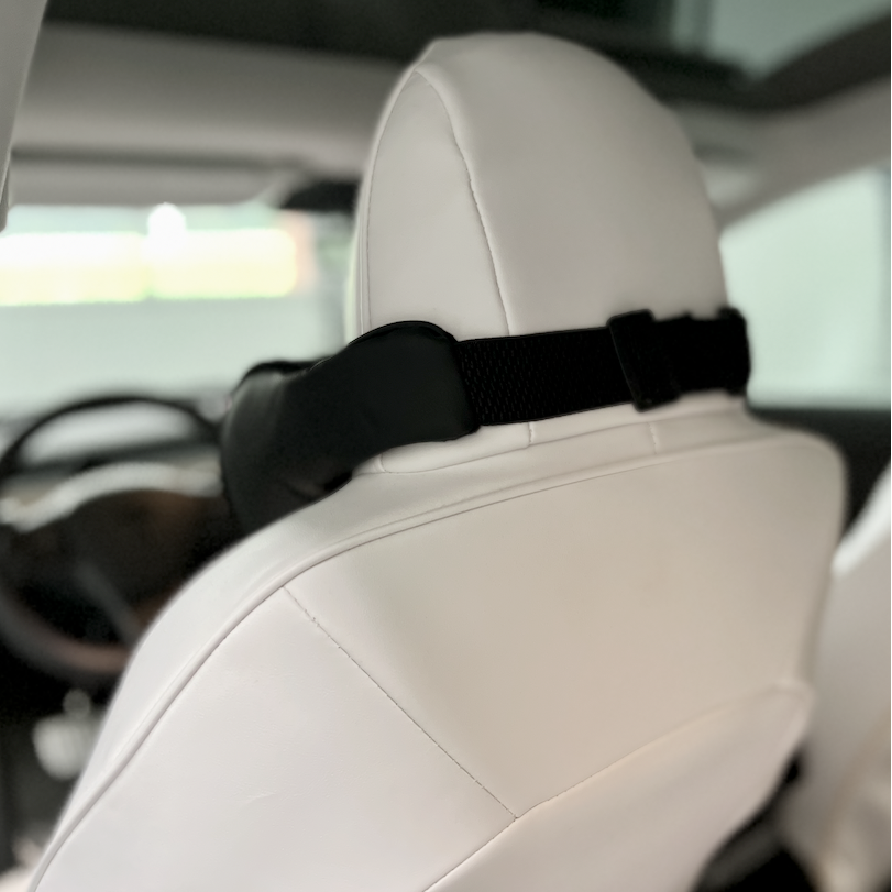 Nackenkissen an der Rückenlehne eines weißen Autositzes für zusätzlichen Komfort auf der Fahrt.