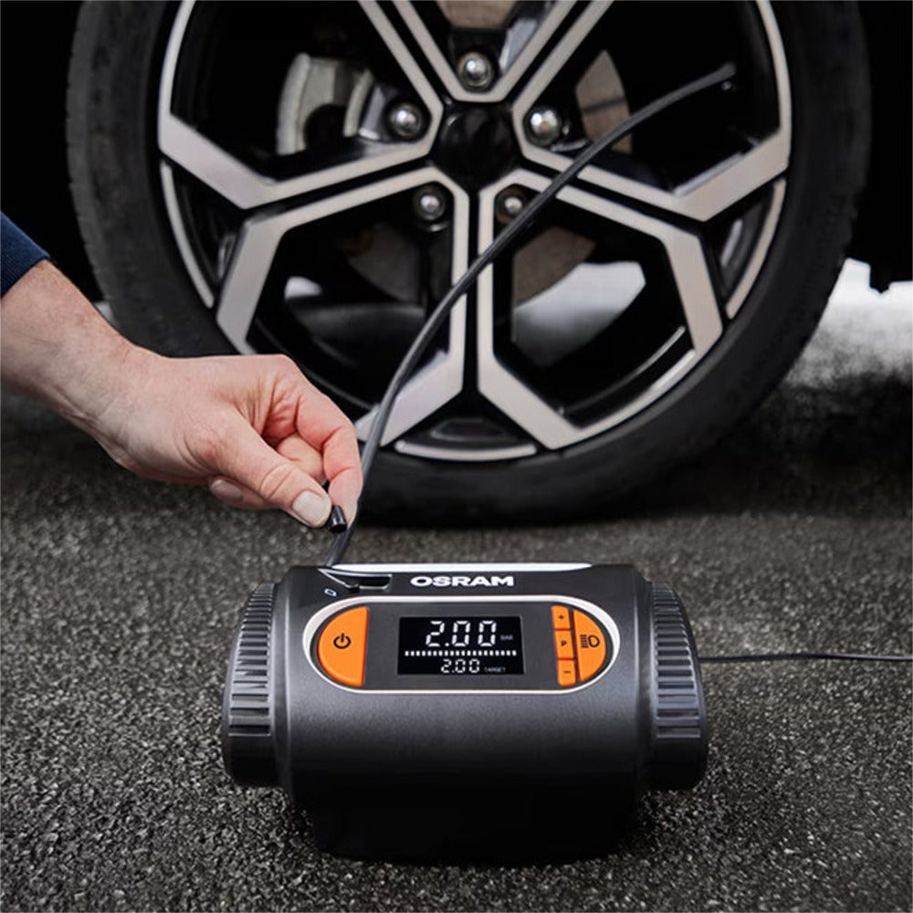 Hånd tilslutter ventildyse på Osram TYREinflate 2120 foran bildæk