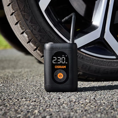 Osram TYREinflate 1600 står på grus foran bildæk, display viser 230 kPa