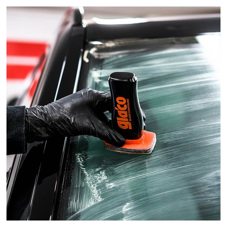 Eine Hand mit schwarzem Handschuh trägt Glaco Glass Compound auf die Autoscheibe auf.