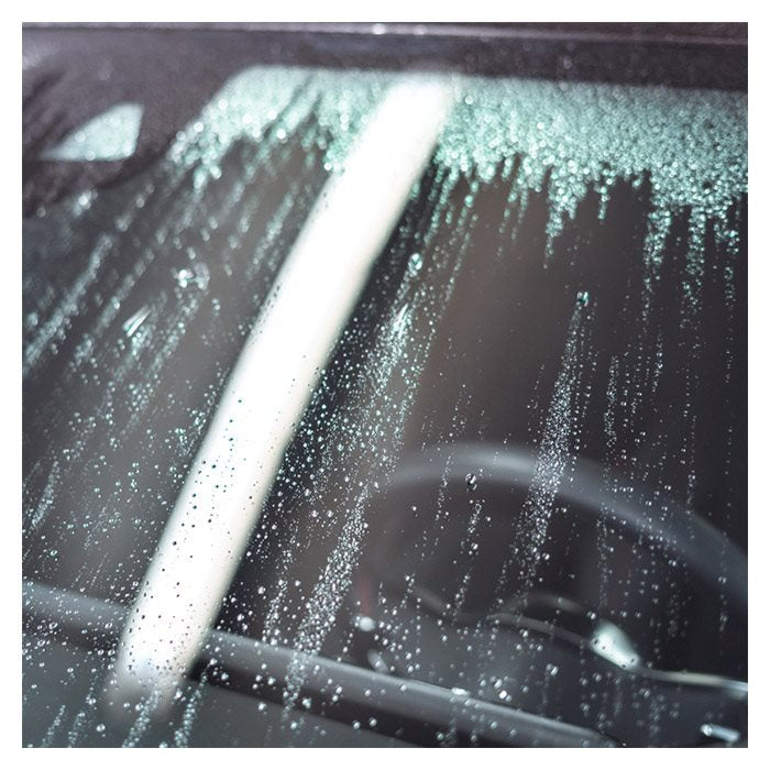 Wassertropfen auf der Autoscheibe nach Behandlung mit Antibeschlagmittel.