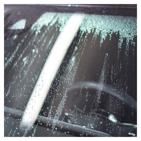 Wassertropfen auf der Autoscheibe nach Behandlung mit Antibeschlagmittel.