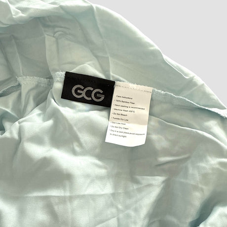 Hellblaues GCG MAX Bambus-Spannbettlaken mit Etiketten, die Waschhinweise und Produktinformationen zeigen.