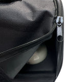 Schwarze Tasche mit offenem Reißverschluss und einer reflektierenden Kugel darin