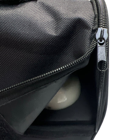 Schwarze Tasche mit offenem Reißverschluss und einer reflektierenden Kugel darin