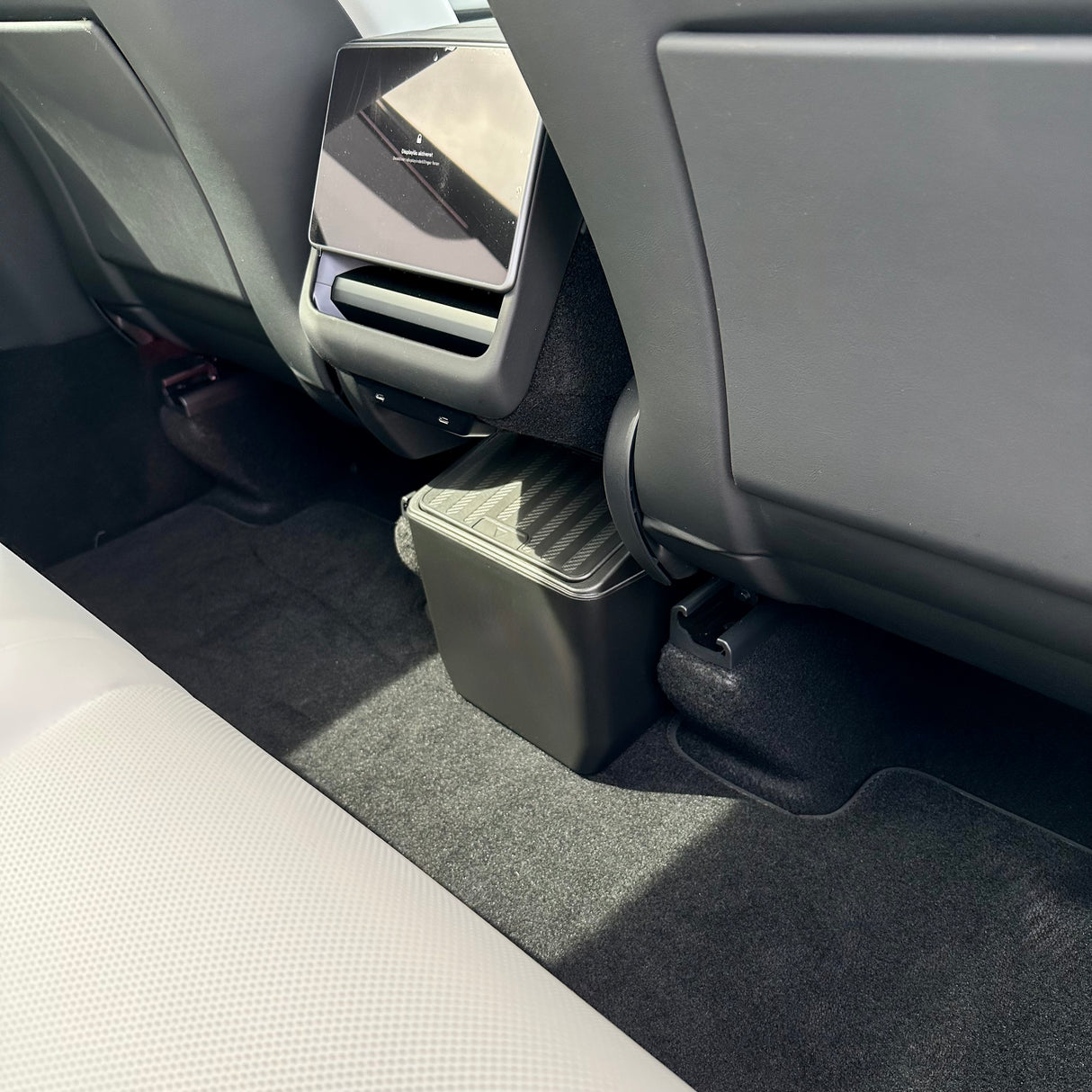 Abfall-Aufbewahrungsbox mit Klickdeckel, platziert am Rücksitz im Tesla Model Y.