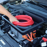 Mann steckt rotes Ladekabel in Rati Frunk Behälter, der in einem Auto montiert ist