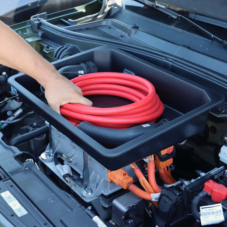 Mann steckt rotes Ladekabel in Rati Frunk Behälter, der in einem Auto montiert ist