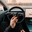 Hand hält S3XY Blinkerhebel vorne am Lenkrad des Tesla Model 3 Highland.