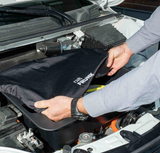 Hände, die eine Schutzabdeckung über die Frunk-Aufbewahrungsbox im Auto legen