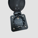 Nahaufnahme eines schwarzen V2L Typ 2 Adapters mit offenem Deckel und 230V Steckdose