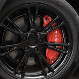 Rote Bremssattel-Abdeckungen mit weißem Tesla-Logo auf einer schwarzen Felge.