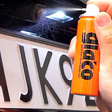 Hand, die Glaco Mirror Coat Zero auf eine Autokamera über dem Nummernschild sprüht.