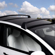 Tesla Model Y mit schwarzen Dachträgern unter einem blauen Himmel mit Wolken